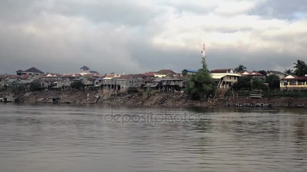 Vesnice chůda domy na břehu řeky při odlivu za temné zatažené obloze (záběr z pohybu lodi) — Stock video