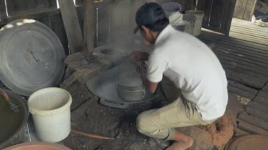 Pirinç hamur kaynar su ile delikli bir kova sarararak adam