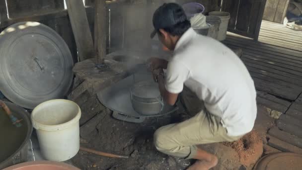 Hombre blanqueando masa de arroz en un cubo hueco con agua hirviendo — Vídeos de Stock