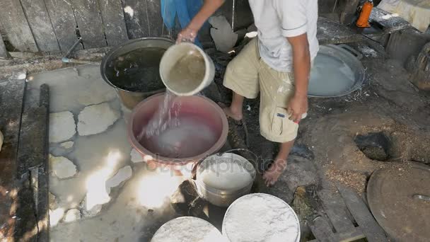Man softening rice noodles with water in a holed bucket — Stock Video