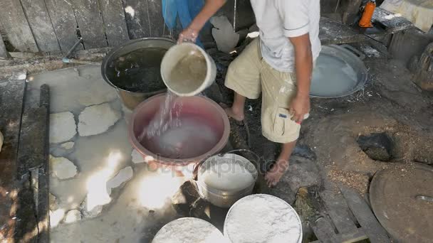 Ο άνθρωπος μαλακώνει noodles ρυζιού με νερό σε ένα κουβά με οπές — Αρχείο Βίντεο