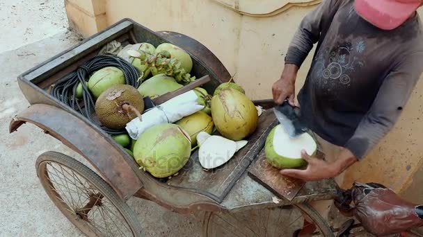 Постачальник кокосової вулиці, який готує питний кокос для клієнтів: зверху відрізаний, отвір зверху і прорізати на стороні з соломою через нього — стокове відео