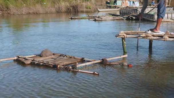 Pescatore sta tirando la rete fuori dall'acqua in piedi su una piccola piattaforma di bambù . — Video Stock