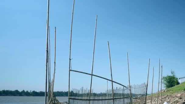 Trampa de pescado hecha a mano hecha de bambú tendida en aguas poco profundas junto al río en un día ventoso — Vídeos de Stock