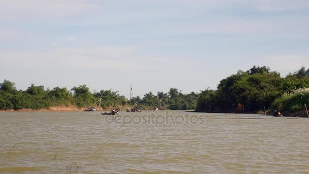 Vista à distância de uma canoa motorizada escavada no rio e barcos com redes de pesca como pano de fundo — Vídeo de Stock