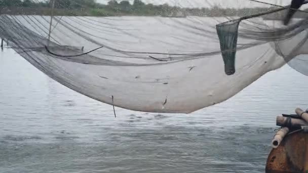 Vista del nivel del agua de la red de pesca de río chino y el pescador que utiliza una red de mano para capturar peces fuera de ella — Vídeos de Stock