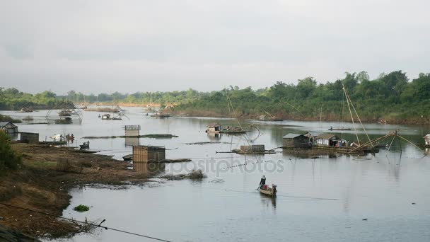 Casas flotantes y redes de pesca chinas en el lago. Fisher remando su barco por la mañana . — Vídeo de stock