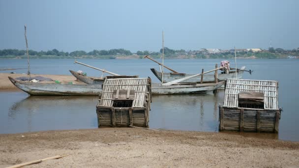 Деревянные ящики для рыбы рядом с маленькими рыбацкими лодками на берегу реки (крупным планом) ) — стоковое видео