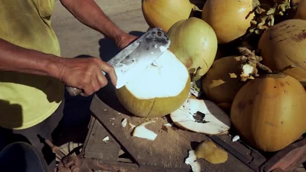 Постачальник кокосових вулиць готує кокос перед подачею клієнтів: зверху відрізають, отвір зверху і прорізають на стороні соломою через неї — стокове відео