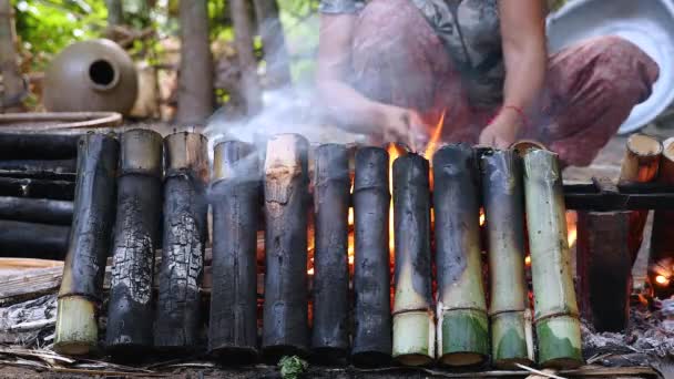 Women turning bamboo cakes cooking on fire — Stock Video