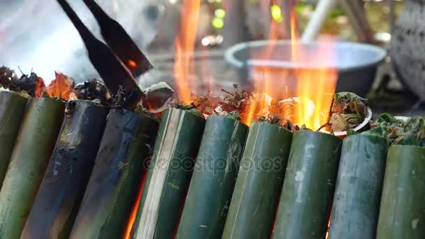 Mulher transformando bolos de bambu cozinhar no fogo — Vídeo de Stock