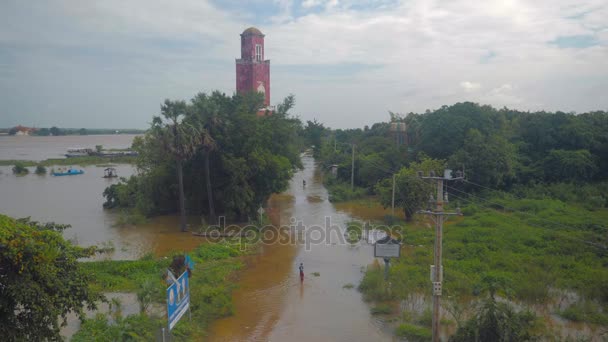 Niños y motocicletas que se desplazan por un pueblo de carretera durante los períodos de inundaciones . — Vídeo de stock