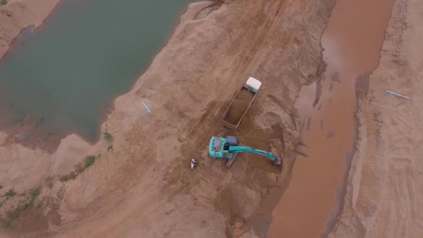 砂をダンプ トラックに読み込んで油圧ショベルのドローン ビュー — ストック動画