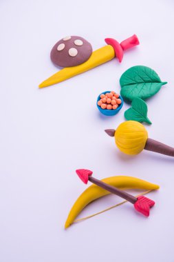 mutlu dussehra, mutlu aayudha pooja veya puja veya mutlu vijayadashami kartpostal fotoğrafı yay ve ok, kılıç gibi silah kil modeli kullanılarak yapılan / kalkan, gadda veya gada ve tatlılar apta ile yaprak