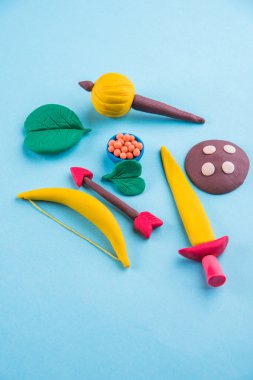 mutlu dussehra, mutlu aayudha pooja veya puja veya mutlu vijayadashami kartpostal fotoğrafı yay ve ok, kılıç gibi silah kil modeli kullanılarak yapılan / kalkan, gadda veya gada ve tatlılar apta ile yaprak