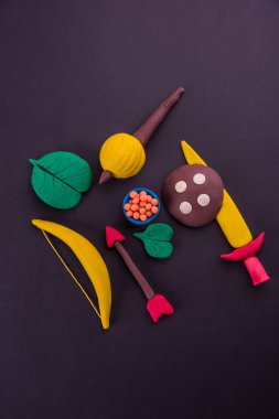 mutlu dussehra, mutlu aayudha pooja veya puja veya mutlu vijayadashami kartpostal fotoğrafı yay ve ok, kılıç gibi silah kil modeli kullanılarak yapılan / kalkan, gadda veya gada ve tatlılar apta ile yaprak
