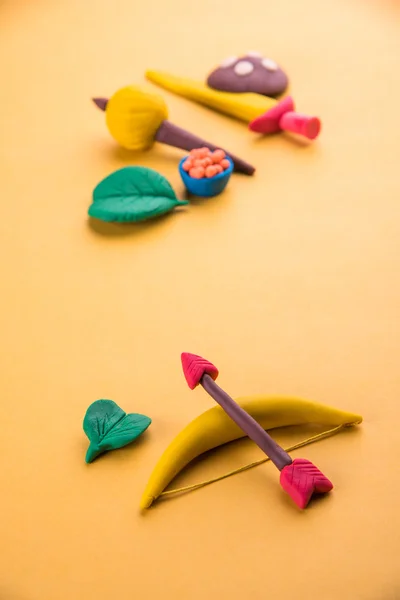 Happy dussehra, happy aayudha pooja oder puja oder happy vijayadashami Grußkarte, die unter Verwendung von Foto von Ton Modell von Waffen wie Pfeil und Bogen, Schwert / Schild, Gadda oder Gada und Süßigkeiten mit apta Blatt gemacht — Stockfoto