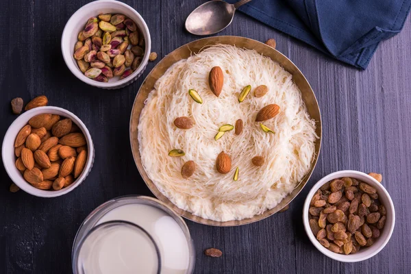 Indian sweet sutarfeni or sutar feni or firni or seviyan or laccha, shredded, flaky-rice-flour roasted in ghee, blended with melted sugar to form a cotton candy, topped with pistachio and almonds