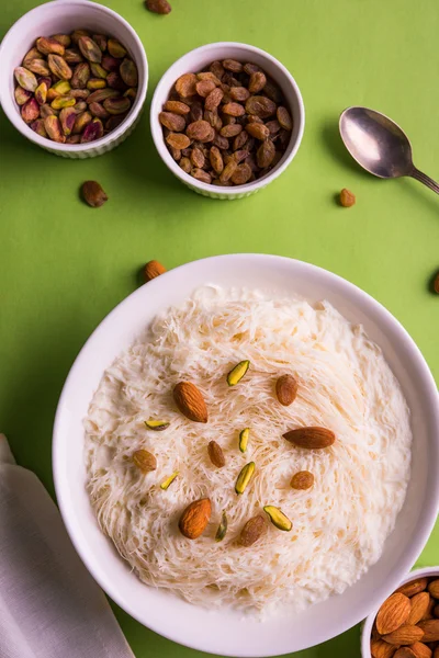 Indian sweet sutarfeni or sutar feni or firni or seviyan or laccha, shredded, flaky-rice-flour roasted in ghee, blended with melted sugar to form a cotton candy, topped with pistachio and almonds