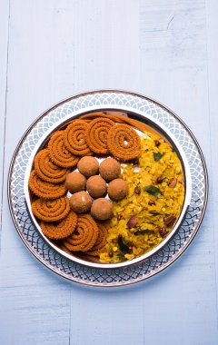 Plate full of indian festival food or diwali food or snacks like laddu, chivda, chakali or murukku, sev and shankar pale, sweet and salty snack food clipart