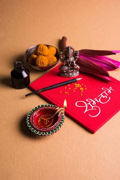 Uma auspiciosa escrita indiana Shubha Labh significa 'Bondade' e 'Riqueza', sobre o livro de notas contábeis vermelho / 'bahi khata' com a deusa Laxmi, diya, doces e lótus e caneta com tinta em laxmi pujan, em diwali — Fotografia de Stock