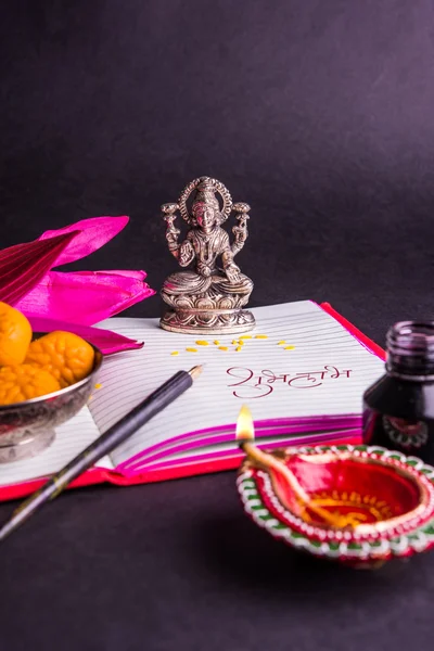 An auspicious Indian writing Shubha Labh means 'Goodness' & 'Wealth', over Red accounting note book / 'bahi khata' with goddess Laxmi, diya, sweets and lotus and pen with ink on laxmi pujan, on diwali — Stock Photo, Image