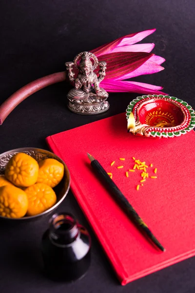 Uma auspiciosa escrita indiana Shubha Labh significa 'Bondade' e 'Riqueza', sobre o livro de notas contábeis vermelho / 'bahi khata' com a deusa Laxmi, diya, doces e lótus e caneta com tinta em laxmi pujan, em diwali — Fotografia de Stock