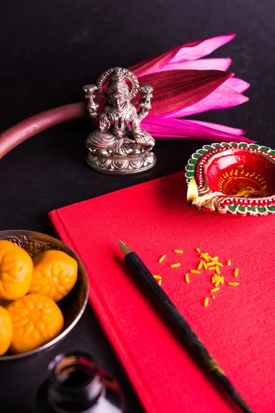 Shubha Labh を書く縁起の良いインド赤メモ帳を会計上の「善」・「富」の意味/ディワリのラクシュミ pujan 上の 'バヒ khata' 女神ラクシュミと diya、お菓子とロータス、ペンとインク — ストック写真