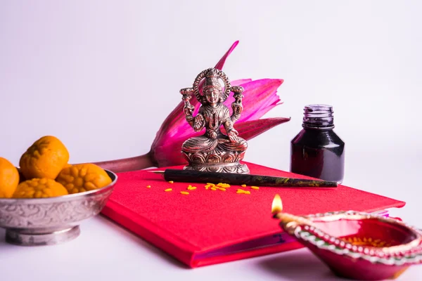 Shubha Labh を書く縁起の良いインド赤メモ帳を会計上の「善」・「富」の意味/ディワリのラクシュミ pujan 上の 'バヒ khata' 女神ラクシュミと diya、お菓子とロータス、ペンとインク — ストック写真