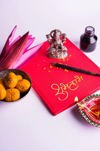 Uma auspiciosa escrita indiana Shubha Labh significa 'Bondade' e 'Riqueza', sobre o livro de notas contábeis vermelho / 'bahi khata' com a deusa Laxmi, diya, doces e lótus e caneta com tinta em laxmi pujan, em diwali — Fotografia de Stock