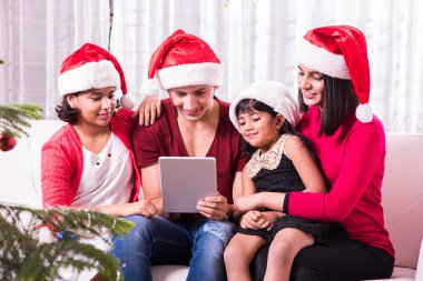 Genç mutlu Kızılderili ya da Asyalı dört kişilik aile Noel arifesinde, mutlu Noeller akıllı telefon veya cep telefonu ya da tablet bilgisayar tarafından kendilerini fotoğraf çekme