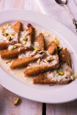 Şahi Tukda ghee, derin kızarmış ekmek hazır - şekerli krema ile garnitür ve meyve kuru. Hint tatlı tabağı