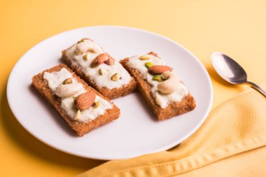 Şahi tukda hazırlanan - derin yağda kızartılmış ekmek ghee içinde şekerli krema ve kuru meyve ile süsleyin.