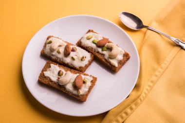 Şahi tukda hazırlanan - derin yağda kızartılmış ekmek ghee içinde şekerli krema ve kuru meyve ile süsleyin.