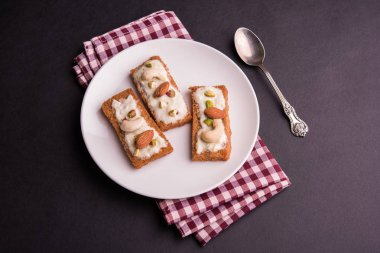 Şahi tukda hazırlanan - derin yağda kızartılmış ekmek ghee içinde şekerli krema ve kuru meyve ile süsleyin.