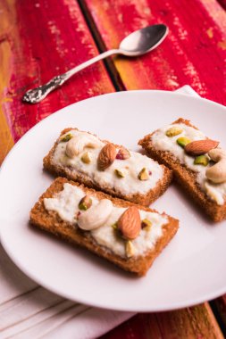 Şahi tukda hazırlanan - derin yağda kızartılmış ekmek ghee içinde şekerli krema ve kuru meyve ile süsleyin.