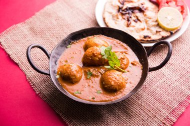 Kaşmir Dum Aloo ya da baharatlı patatesli köri, taze krema ve kişniş ile süslenmiş. Renkli bir geçmişi olan, Naan / Roti ile birlikte bir Karahi 'de hizmet vermiş. Seçici odak