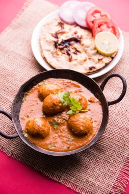 Kaşmir Dum Aloo ya da baharatlı patatesli köri, taze krema ve kişniş ile süslenmiş. Renkli bir geçmişi olan, Naan / Roti ile birlikte bir Karahi 'de hizmet vermiş. Seçici odak