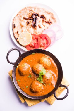 Kaşmir Dum Aloo ya da baharatlı patatesli köri, taze krema ve kişniş ile süslenmiş. Renkli bir geçmişi olan, Naan / Roti ile birlikte bir Karahi 'de hizmet vermiş. Seçici odak