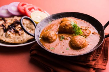 Kaşmir Dum Aloo ya da baharatlı patatesli köri, taze krema ve kişniş ile süslenmiş. Renkli bir geçmişi olan, Naan / Roti ile birlikte bir Karahi 'de hizmet vermiş. Seçici odak