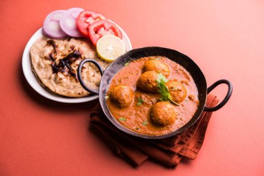 Kaşmir Dum Aloo ya da baharatlı patatesli köri, taze krema ve kişniş ile süslenmiş. Renkli bir geçmişi olan, Naan / Roti ile birlikte bir Karahi 'de hizmet vermiş. Seçici odak