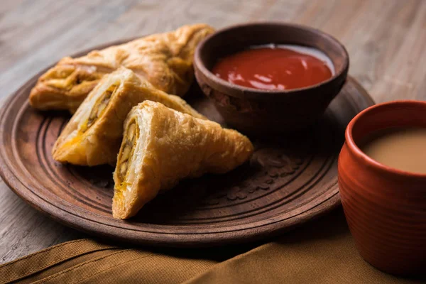 Stuffed vegetable or veg puff or puf or samosa, famous indian snack menu, served with hot tea, selective focus — Stock Photo, Image