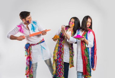 İki Hintli güzel kız ve erkek Holi festivalini kutluyorlar. Hint geleneksel giysileri ve dupatta renginde, beyaz arka planda, kopyalama uzayı ile izole edilmiş.