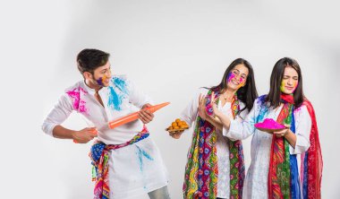 İki Hintli güzel kız ve erkek Holi festivalini kutluyorlar. Hint geleneksel giysileri ve dupatta renginde, beyaz arka planda, kopyalama uzayı ile izole edilmiş.