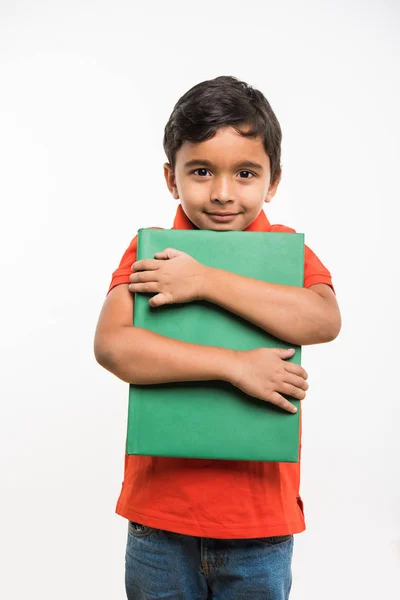 Щаслива індійська дитина тримає або обіймає велику книгу на білому тлі — стокове фото