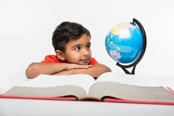 Criança indiana observando ou estudando modelo globo educacional com lupa — Fotografia de Stock