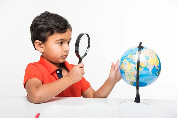 Niño indio observando o estudiando el modelo de globo educativo con lupa — Foto de Stock