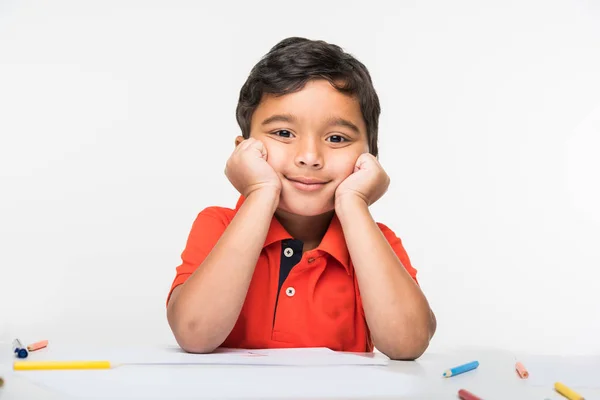 Mutlu Hint çingene çocuk çocuk okul masada oturan izole beyaz zemin üzerine Hint çocuk masada çene ile her iki elleri üzerinde oturuyor. — Stok fotoğraf