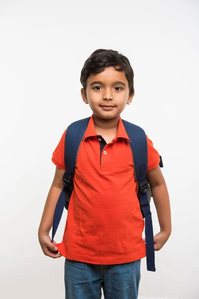 Індійський милий хлопчик, який виходить або ходить до школи з маленькою шкільною сумкою, ізольований на білому тлі — стокове фото