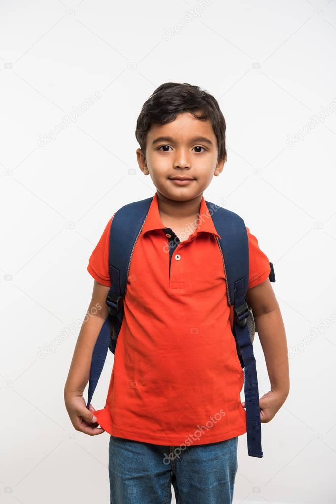 indian cute kid or boy leaving or going to school with small school bag, isolated over white background